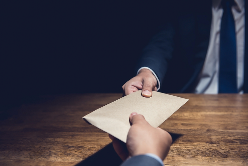 man giving bribe money in a brown envelope