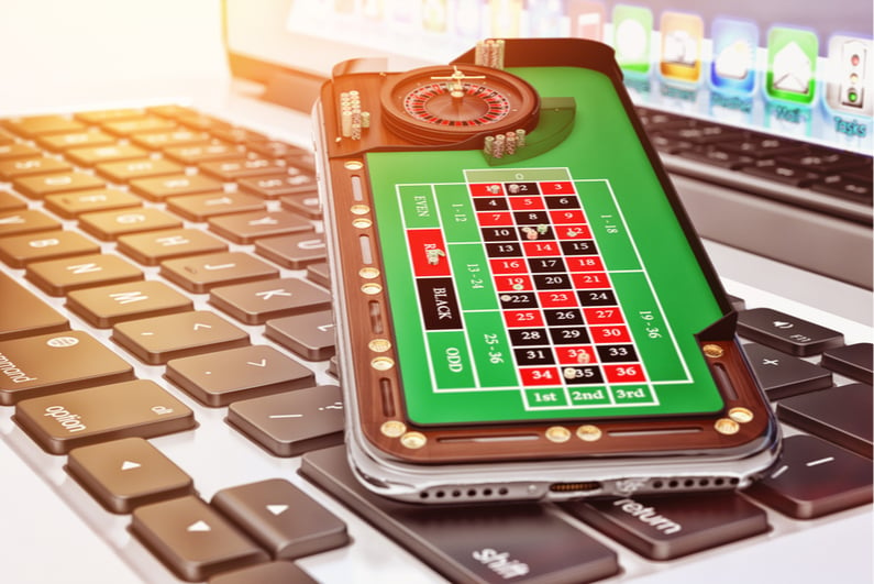 Artistic rending of a smartphone with a mobile casino app sitting on a laptop keyboard