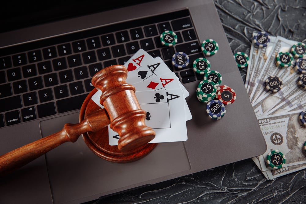 judge's gavel, Ace cards, poker chips, and US dollar bills with laptop in background