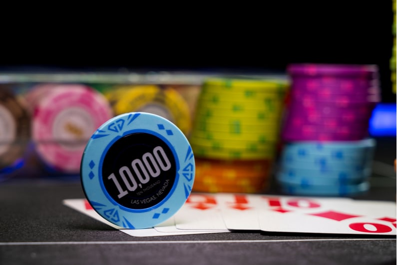 $10,000 chip on a poker table with stacks of chips in the background