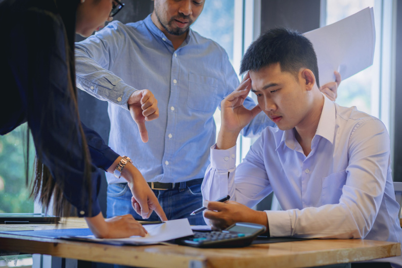 Frustrated man getting a thumbs-down from a co-worker